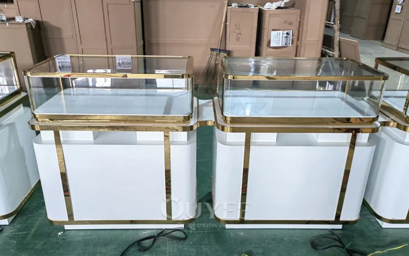 White and gold glass jewelry showcases with paired display sections in the workshop